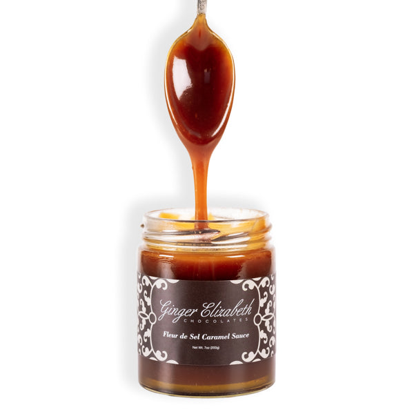 Fleur de Sel Caramel Sauce Jar with dipped spoon above on white background