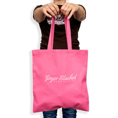 Ginger Elizabeth Chocolates Azaela Pink cotton canvas tote bag with floral G logo, tote  held out by Ginger on white background