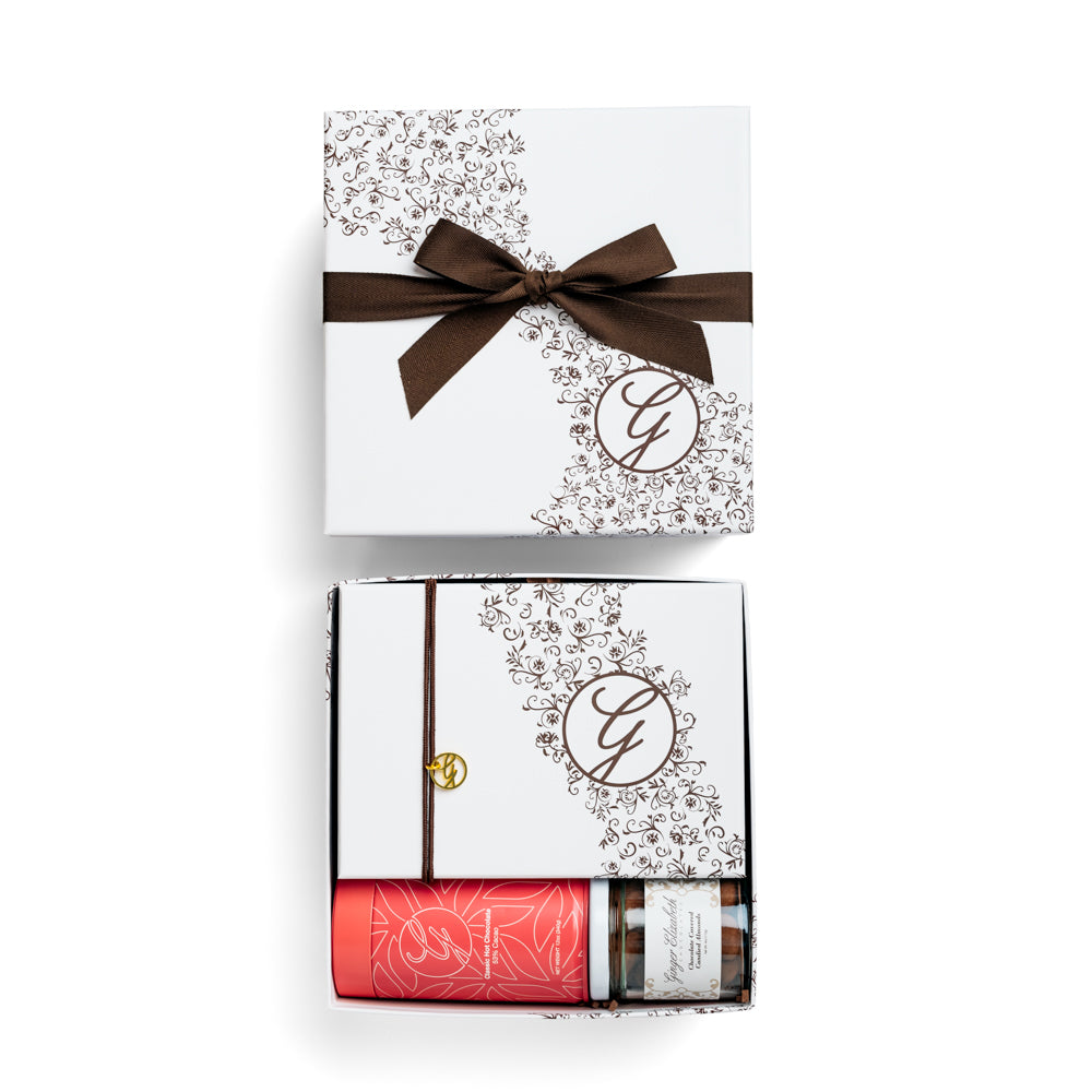 Gift box packaged with 24 piece chocolate box, hot chocolate tin and jar of almonds showing with lid above on white background.