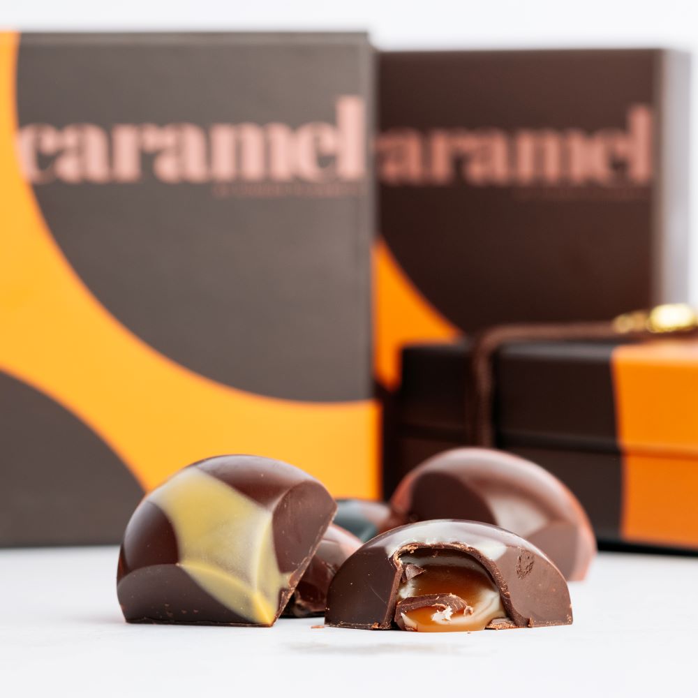 caramel chocolates arranged in front of closed boxes on white background