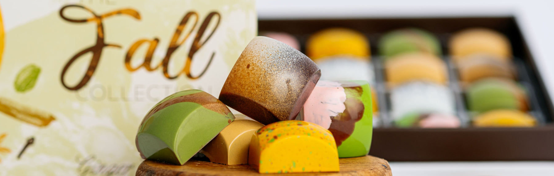 Assorted colorful candies on a wooden board with a 'Fall' themed background