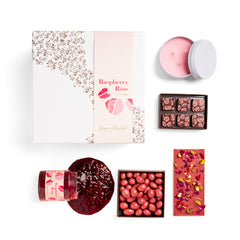 Ginger Elizabeth Chocolates Raspberry Rose Giftbox with decorative sleeve shown with open candle tin, open 6 piece Chocolate box, dessert bar, open covered almonds box and open jam jar with jam spilling out on white background. 