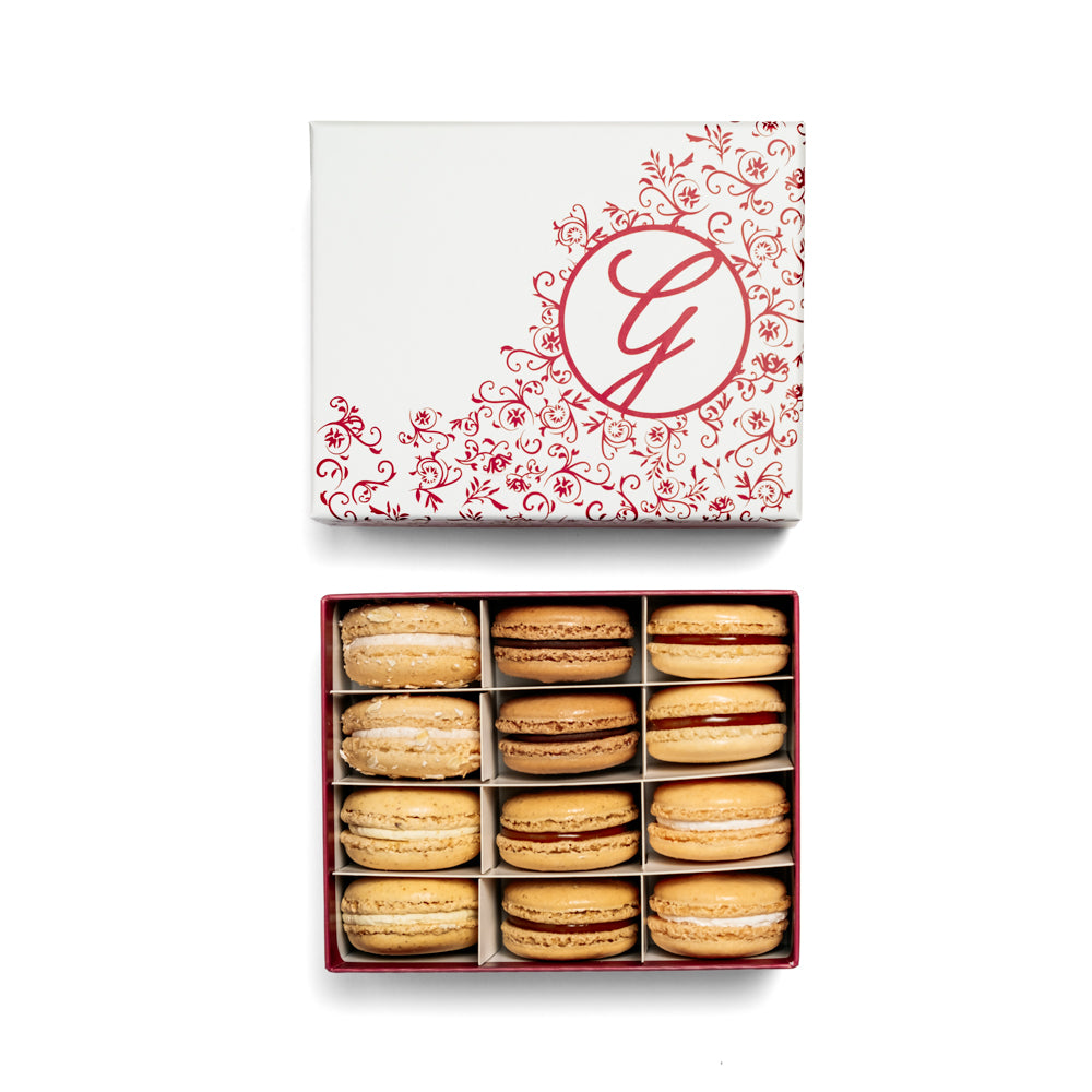 boxed assortment of macarons with floral filigree pink G logo box lid above on white background
