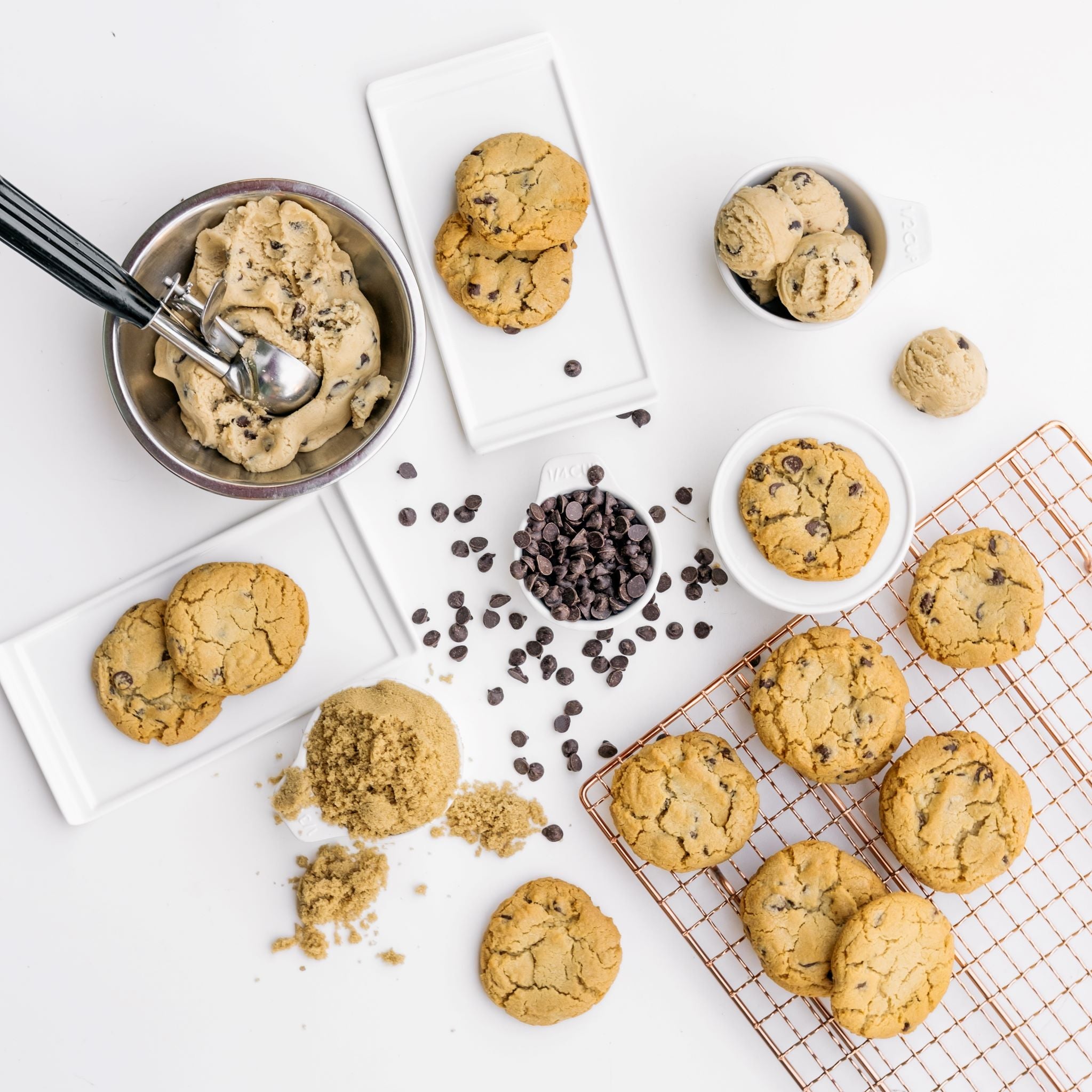 Ginger Elizabeth Chocolates Chocolate Chip Cookies  on plates and baking rack with cookie dough and chocolates chips on white background