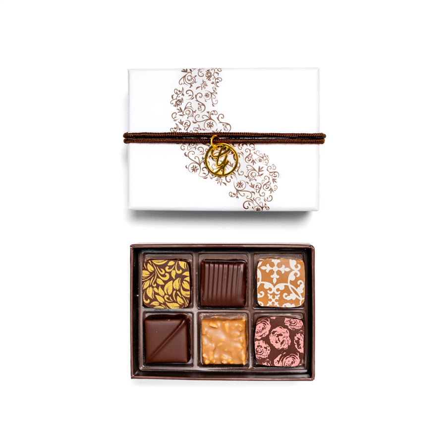 open 6-piece chocolate box arranged below closed box on white background