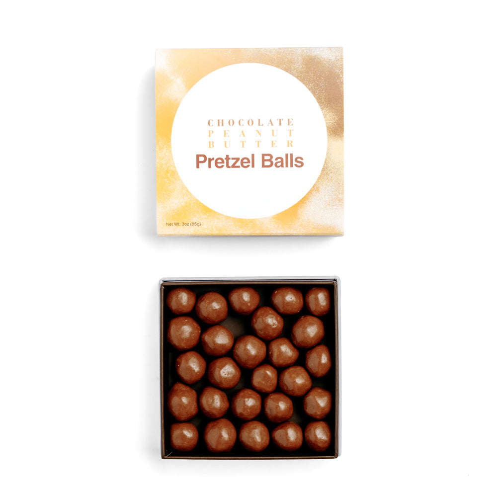 Chocolate peanut butter pretzel balls in box with lid above on white background
