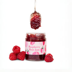 Ginger Elizabeth Chocolates Raspberry Rose jam jar with dipped spoon above and fresh raspberries on white background 