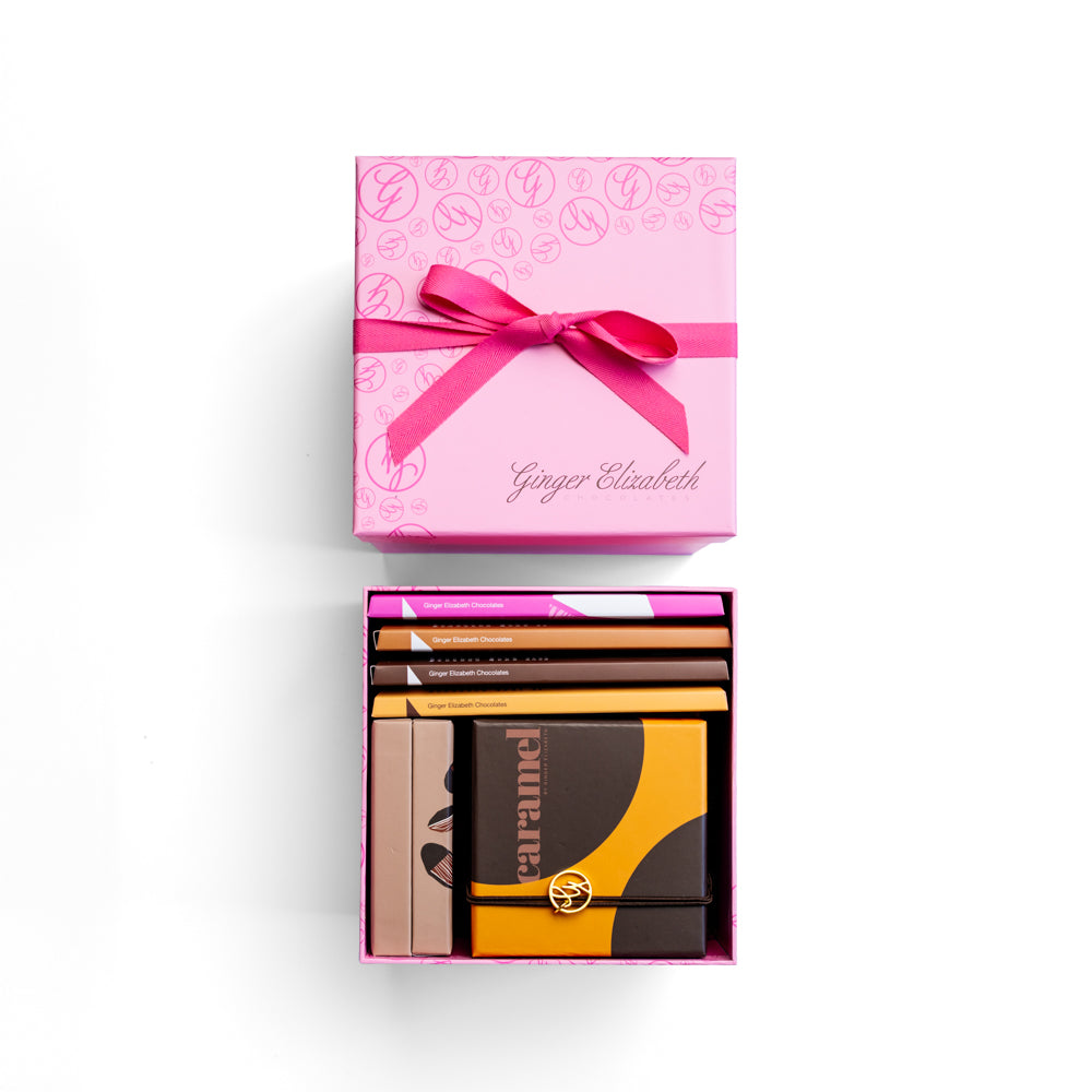 Pink gift box with a bow containing chocolate bars and confections on a white background on a white background