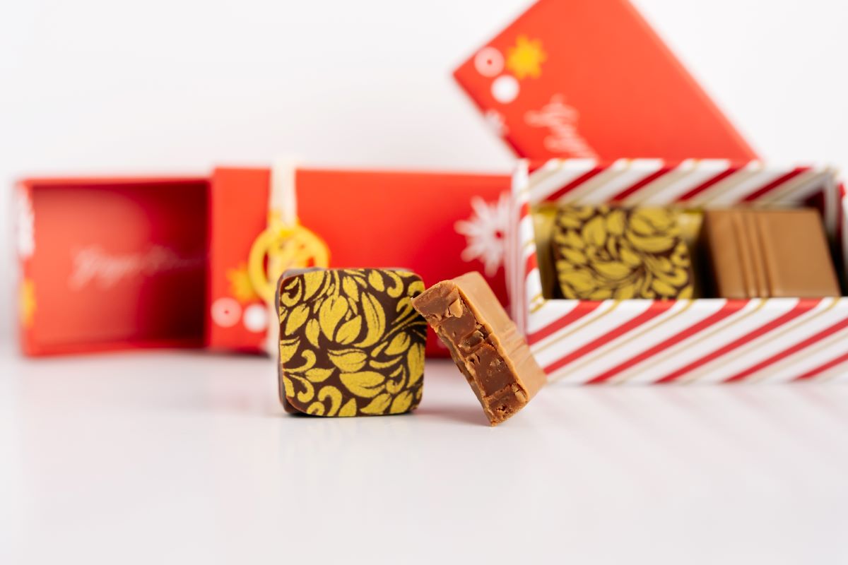 Close up of Ginger Elizabeth 2 piece chocolates in foreground with open and closed boxes blurred  in the background