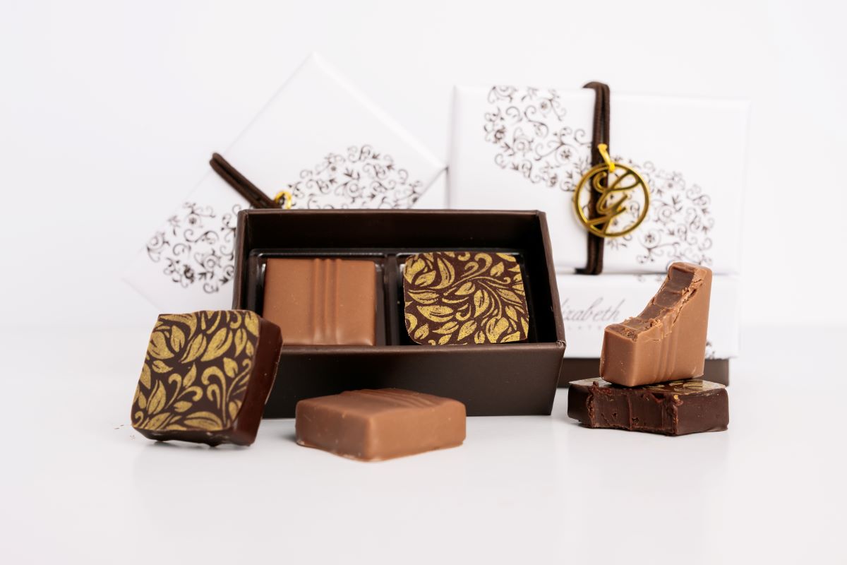 Multiple 2 piece chocolate boxes arranged with loose chocolates on a white background