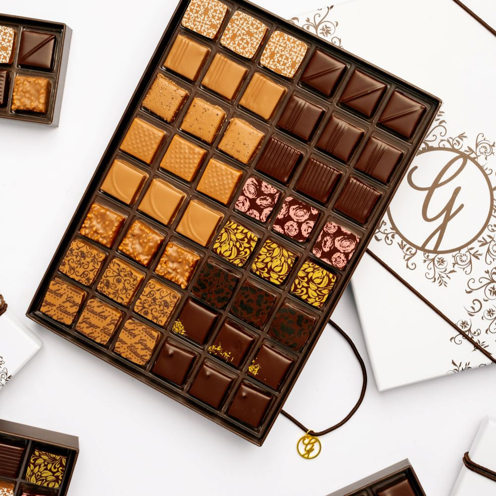 open full 48-piece chocolate box arranged with open and closed boxes on white backgound 