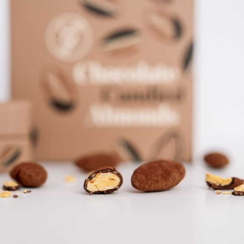 Chocolate-covered almonds with a branded box in the background