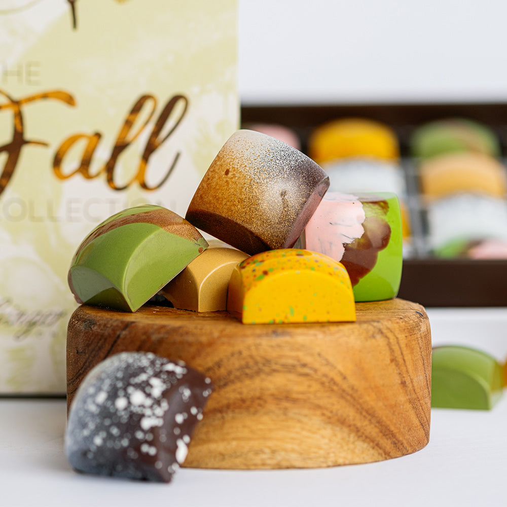 Fall Collection bonbons arranged on upside down wood bowl with box lid and open box in background. 