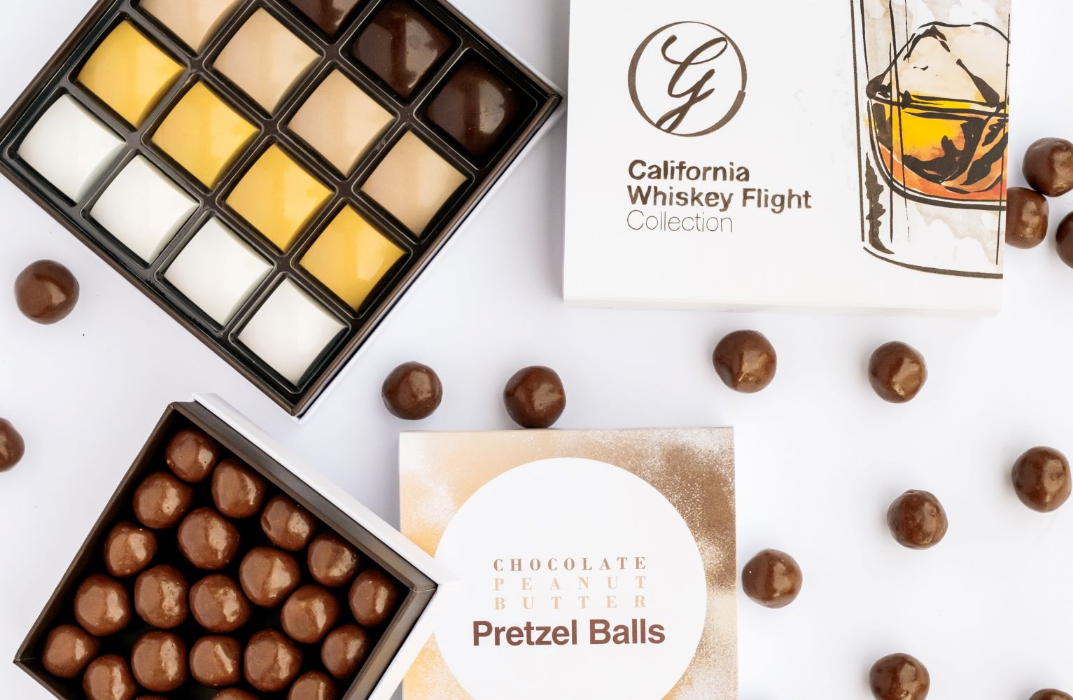 Boxes of California whiskey flight collection and chocolate peanut butter balls surrounded by chocolate balls on white background