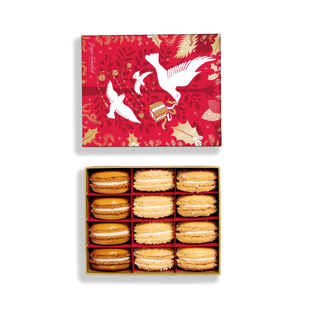 Ginger Elizabeth Chocolates open 12 Piece holiday collection macaron box  with red holiday lid featuring  doves, wrapped presents and holiday greenery in white and gold all on white background.