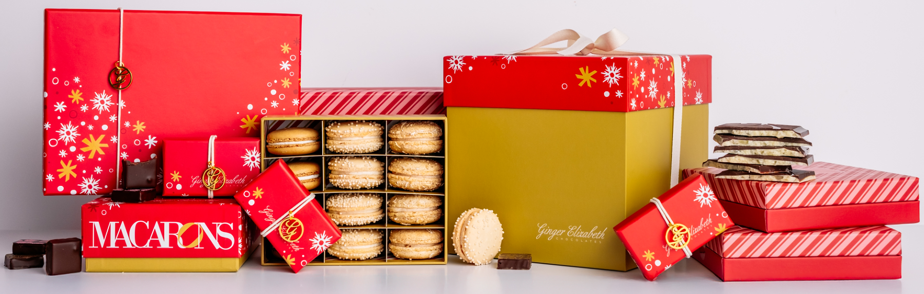 Red gift box with white text and decorative elements next to a box of macarons.