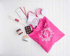 Ginger Elizabeth Chocolates Azaela Pink cotton canvas tote bag with floral G logo on white background with packaged  Chocolates, candle, soap, marshmallow baton, jam and chocolate bars