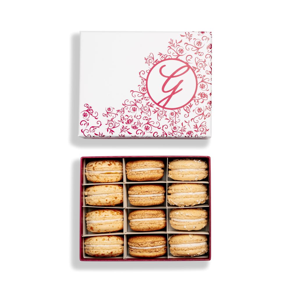 boxed assortment of macarons with floral filigree pink G logo box lid above on white background