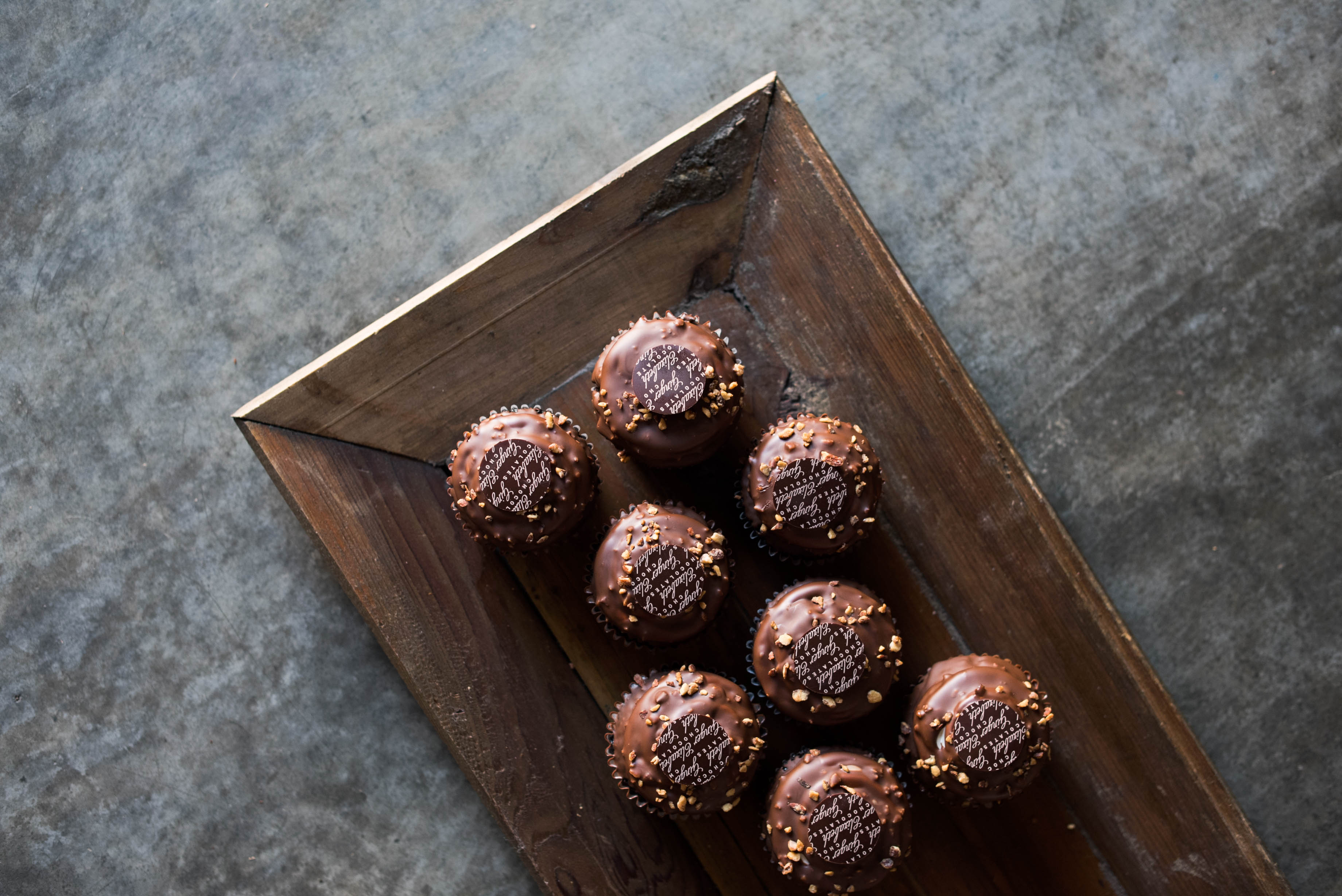 Ginger Elizabeth Chocolates Cupcakes on dark wood tray on concrete countertop