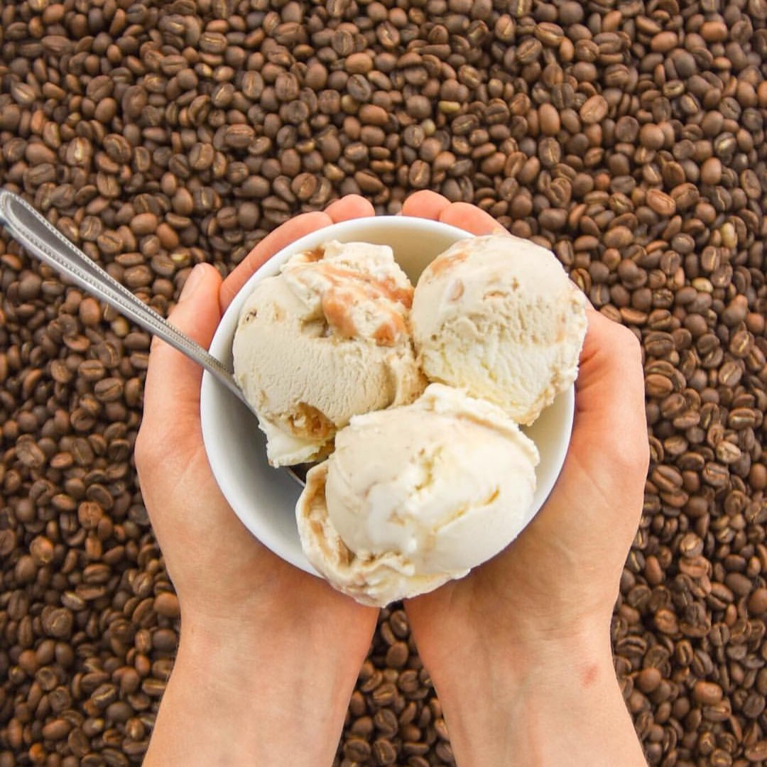 Bowl with 3 scoops of Coffee Whiskey Cookie Dough Ice Cream shown from above, held over coffee beans