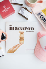 Ginger Elizabeth Chocolates Macaron Cookbook shown with miscellaneous home goods on white background