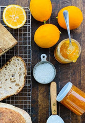 Meyer Lemon Marmalade shown with crusty bread and whole meyer lemons on wood background